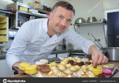 Baker holding tray of cakes